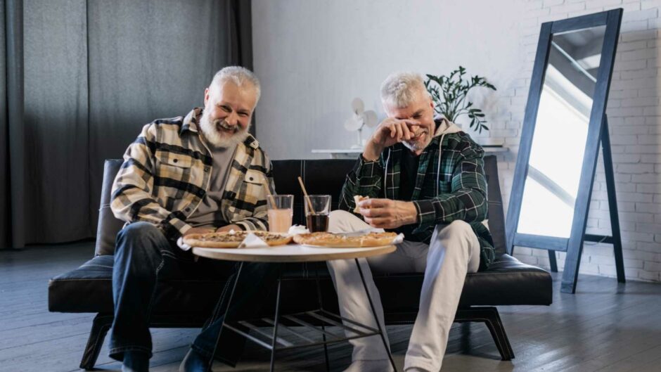 Elderly men enjoying pizza.